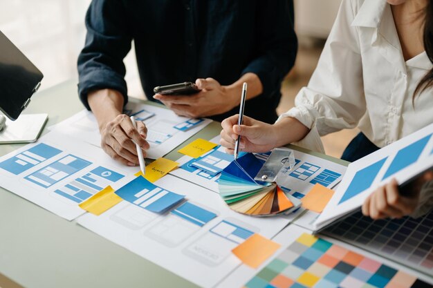 UX-Entwickler und UI-Designer beim Brainstorming über das Wireframe-Design der mobilen App-Schnittstelle mit Kundeninformationen und Farbcode bei officexA
