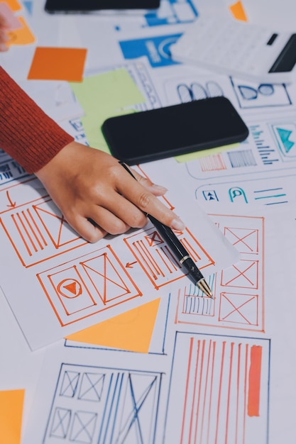 UX UI designer testing prototype on a phone discussing and brainstorming on wireframes for a website and mobile app prototype in the concept of website and mobile application design concept