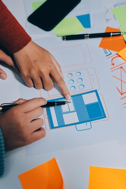 UX UI designer testing prototype on a phone discussing and brainstorming on wireframes for a website and mobile app prototype in the concept of website and mobile application design concept