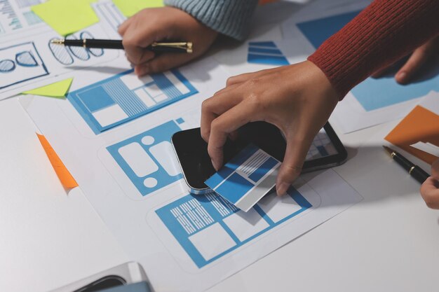 UX UI designer testing prototype on a phone discussing and brainstorming on wireframes for a website and mobile app prototype in the concept of website and mobile application design concept