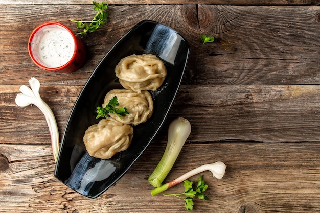 Uzbek preparou bolinhos manti cozidos ou manty em uma tigela tradicional no lugar de receita de menu de banner de mesa de madeira para texto