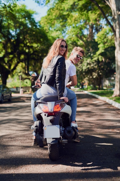 Vá explorar com aquele que você adora foto retrovisor de um jovem casal atraente andando de scooter pela cidade