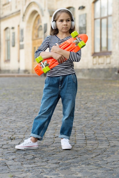 Vacaciones activas. Niño pequeño sostenga el tablero de centavo al aire libre. El skate como medio de transporte. Viaje de patinaje. Libertad y ocio. Salud y recreación. Actividades deportivas. Viaje de aventura. Vacaciones de verano.