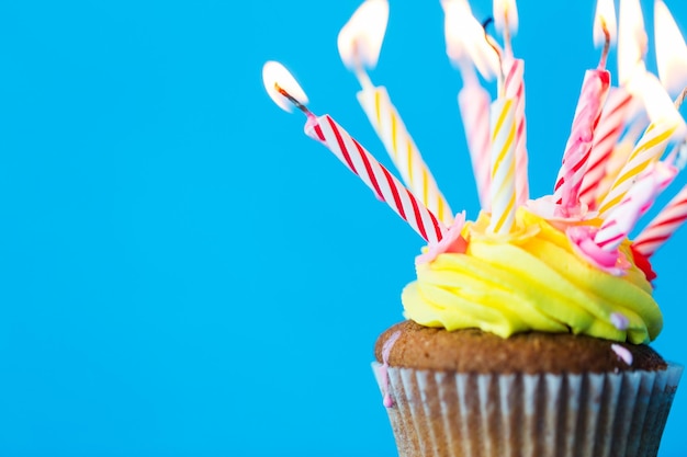 vacaciones, celebraciones, saludos y concepto de fiesta - bizcocho de cumpleaños con muchas velas encendidas sobre fondo azul