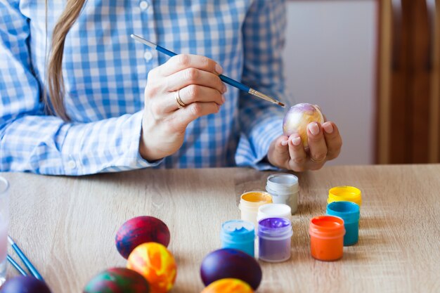 Vacaciones, concepto hecho a mano y creación - Feliz joven se basa en el huevo de Pascua, primer plano.