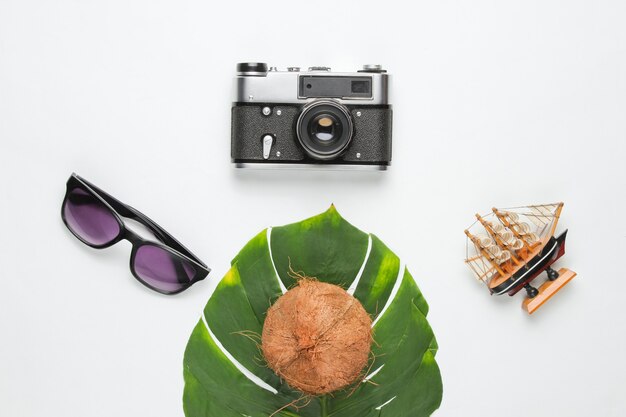 Vacaciones creativas en el fondo del mar. Accesorios de playa de viaje sobre fondo con hoja verde monstera. Vista superior