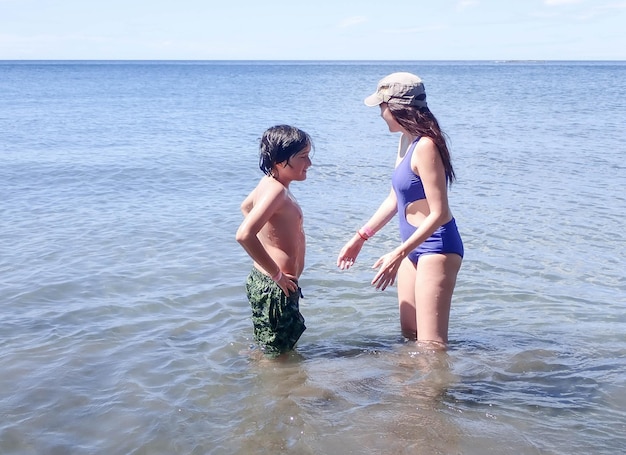 Foto vacaciones de verano, madre e hijo pequeño disfrutando de la playa