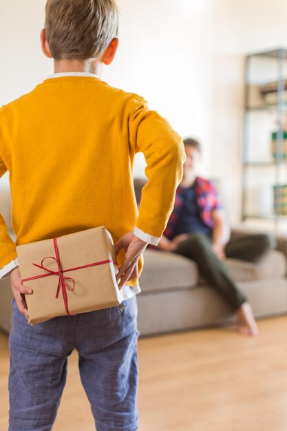 Vacaciones del día del padre Un niño lindo le está dando una caja de regalo hecha a mano a su padre Feliz tiempo en familia juntos, quédense en casa