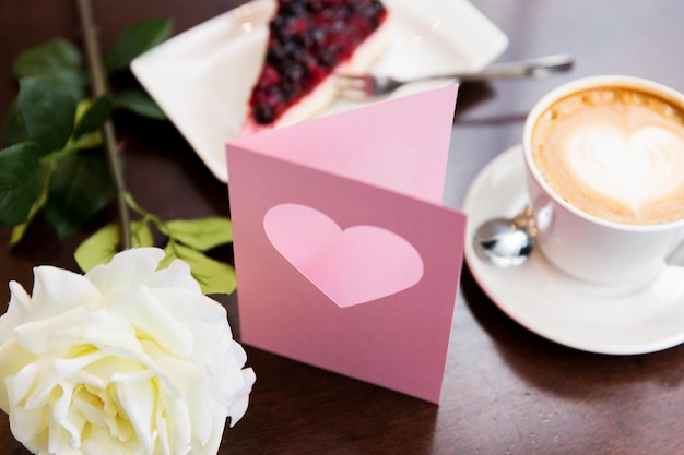 vacaciones, día de san valentín y concepto de amor - cierre de tarjeta de saludo con corazón, flor, pastel y café