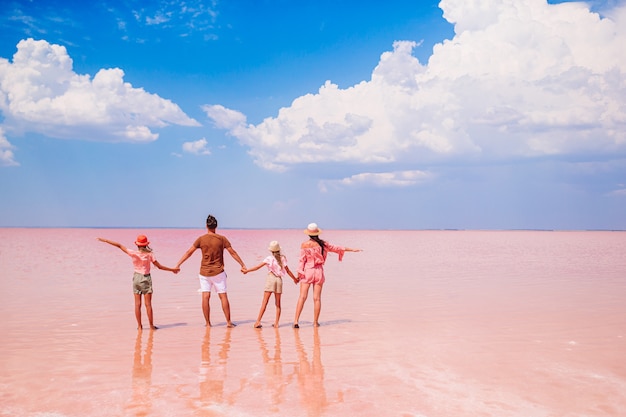 Vacaciones familiares. Felices padres con dos hijos en un lago de sal rosa. Hermosa naturaleza y asombroso paisaje