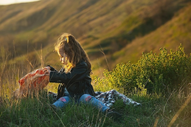 vacaciones familiares por la noche en la naturaleza, una niña rizada se sienta en el suelo