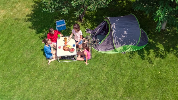 Vacaciones familiares en la vista aérea superior del campamento desde arriba, los padres y los niños se relajan y se divierten en el parque, la carpa y el equipo de campamento debajo del árbol, la familia en el concepto de campamento al aire libre