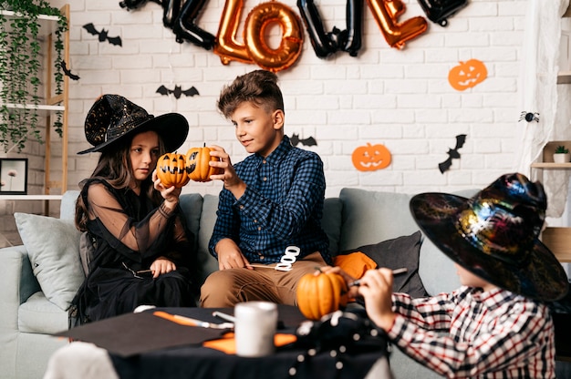 Foto vacaciones de halloween y concepto de infancia niños sonrientes con calabazas en casa