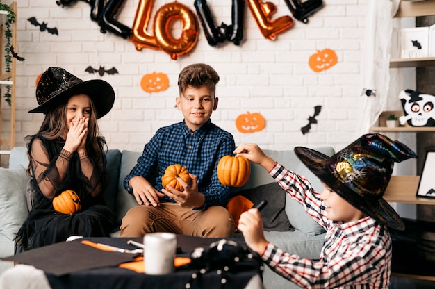 Foto vacaciones de halloween y concepto de infancia niños sonrientes con calabazas en casa