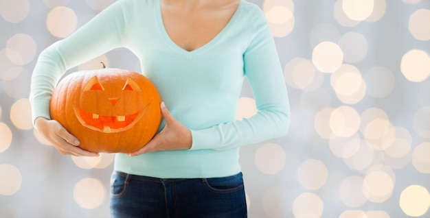 vacaciones, halloween, decoración y concepto de personas - cerca de mujer con calabaza tallada