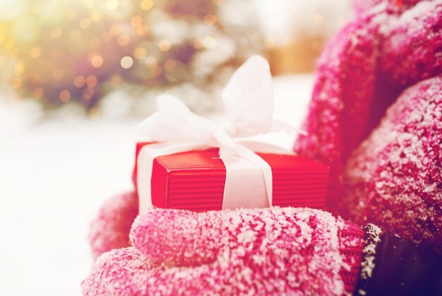 Foto vacaciones de invierno, navidad y concepto de personas - primer plano de manos de mujeres sosteniendo regalos o cajas de regalos al aire libre