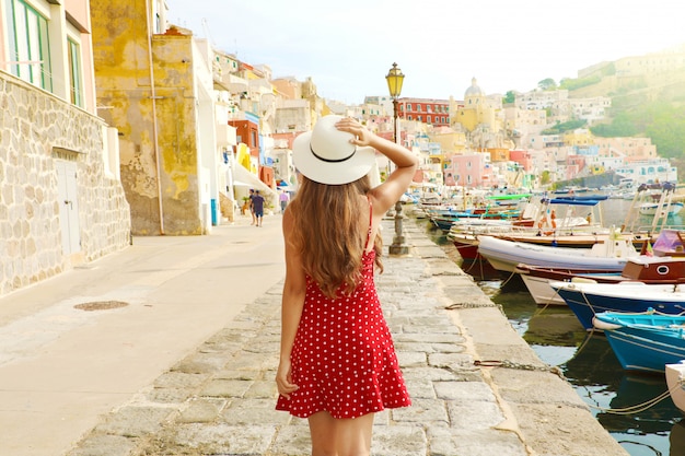 Vacaciones en Italia. Vista posterior de la hermosa niña en el impresionante puerto colorido de Procida en Italia.