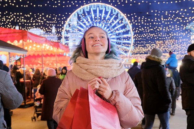 Vacaciones de Navidad y año nuevo, feliz jovencita con bolsas rojas en el mercado de Navidad