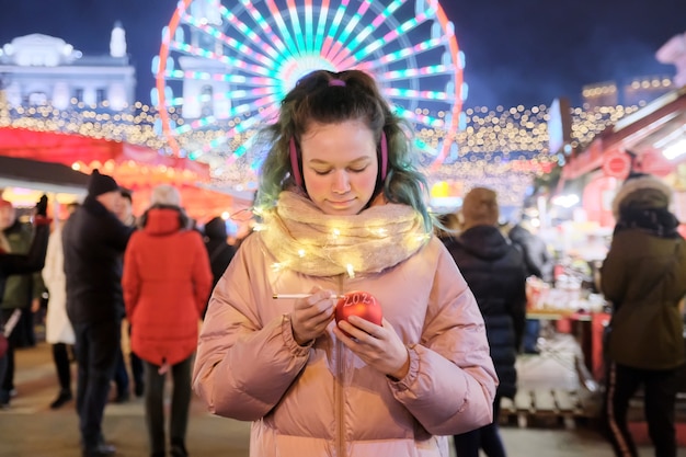 Vacaciones de Navidad y año nuevo, niña feliz escribe en el texto rojo de la bola de Navidad 2021 en el mercado de Navidad