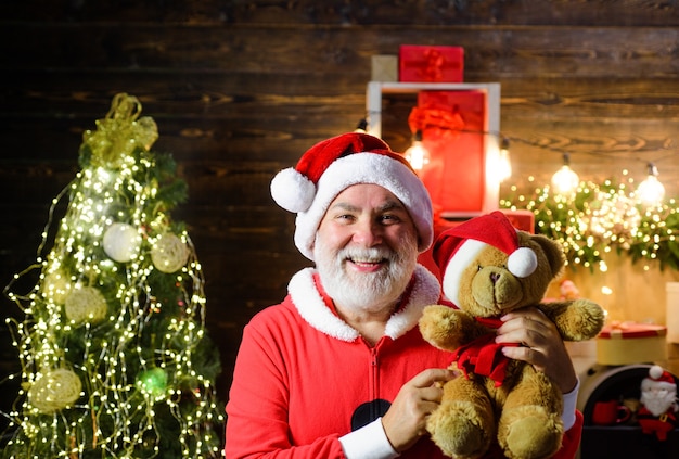 Vacaciones de navidad santa claus hombre barbudo disfrazado de santa claus mantenga muñeco de peluche navidad