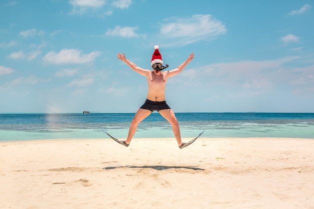 Vacaciones navideñas - hombre con sombrero de santa en la playa tropical de Maldivas