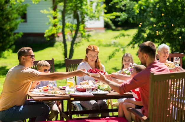 vacaciones de ocio y personas concepto familia feliz teniendo cena festiva o fiesta de jardín de verano