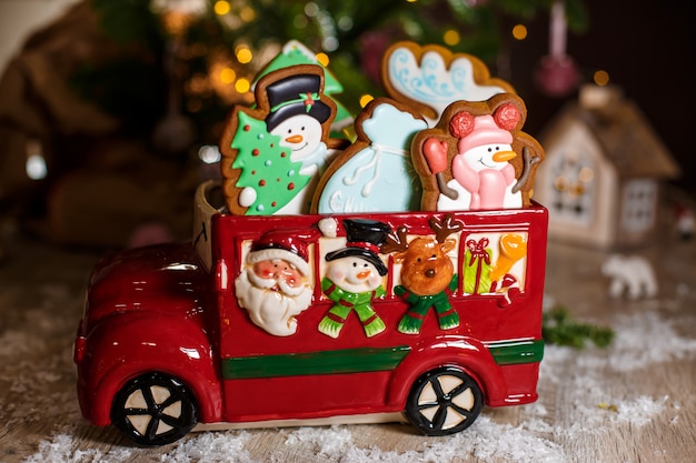 Vacaciones panadería comida tradicional. Coche de juguete decorativo con tortas de pan de jengibre de Navidad en una acogedora decoración cálida con luces de guirnaldas