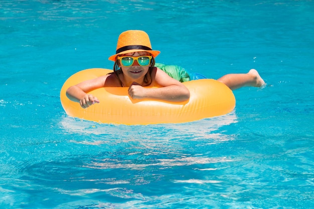 Vacaciones y recreación de verano con niños niño niño años nadar en anillo flotante en natación