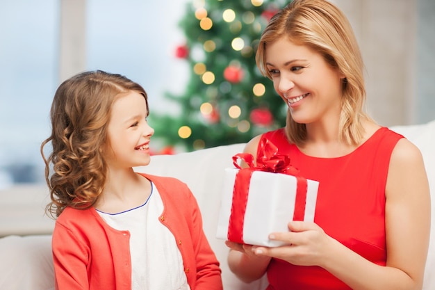 vacaciones, regalos, navidad, concepto de navidad - feliz madre e hija niña con caja de regalo