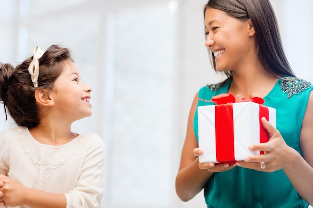 vacaciones, regalos, navidad, concepto de navidad - feliz madre e hija niña con caja de regalo