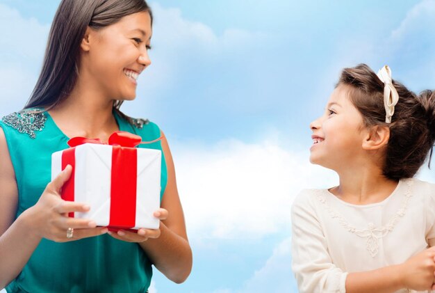 vacaciones, regalos, navidad, concepto de navidad - madre feliz y niña con caja de regalo