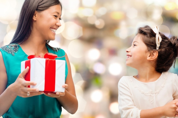 vacaciones, regalos, navidad, familia, niño y concepto de navidad - madre feliz y niña con caja de regalo