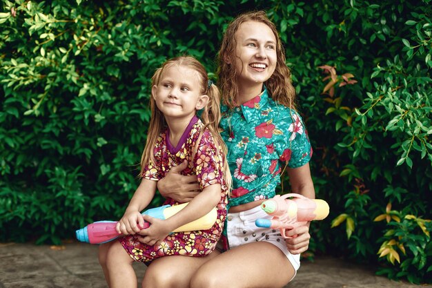 Vacaciones de Songkran Camisa hawaiana de chica divertida y mujer joven con pistola de agua de color plástico Vacaciones tailandesas. Año nuevo tailandés