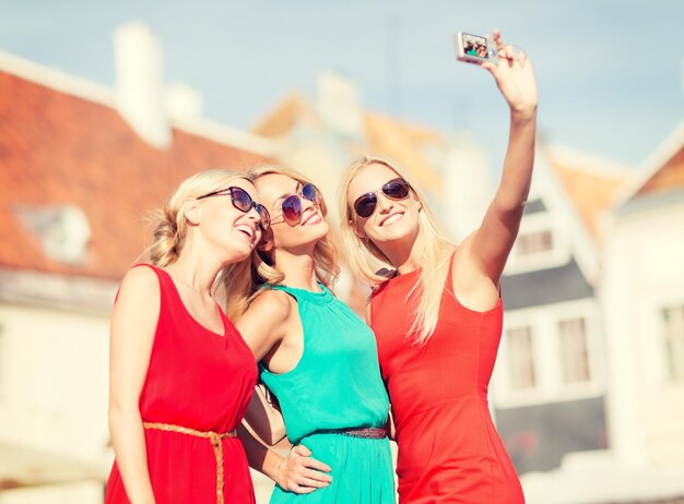 vacaciones y turismo, concepto de tecnología moderna - hermosas chicas tomando fotos en la ciudad