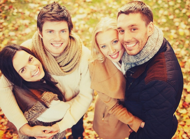 vacaciones, vacaciones, concepto de gente feliz - grupo de amigos o parejas divirtiéndose en el parque de otoño