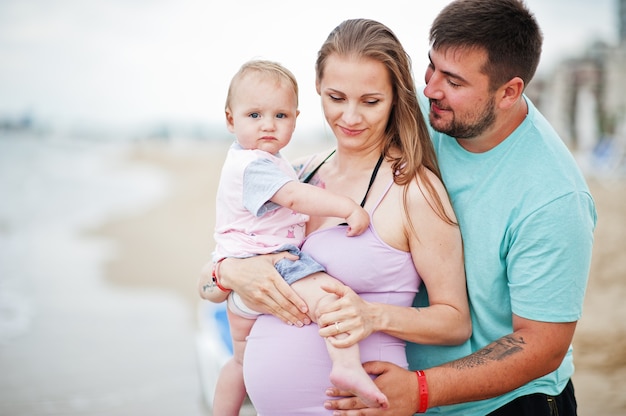 Vacaciones de verano. Actividad al aire libre de padres y personas con niños. Felices vacaciones en familia. Padre, madre embarazada, hija en la playa de arena de mar.