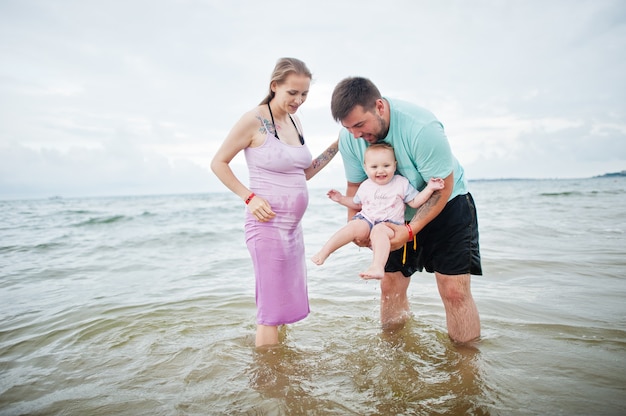 Vacaciones de verano. Actividad al aire libre de padres y personas con niños. Felices vacaciones en familia. Padre, madre embarazada, hija en la playa de arena de mar.