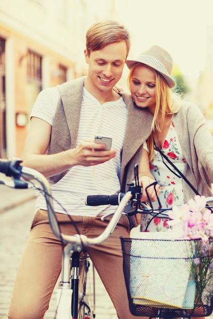 vacaciones de verano, amor, navegación, gps y concepto de citas - pareja con bicicletas y smartphone en la ciudad