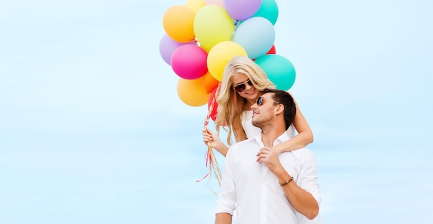 vacaciones de verano, celebración y concepto de citas - pareja con globos de colores en la playa