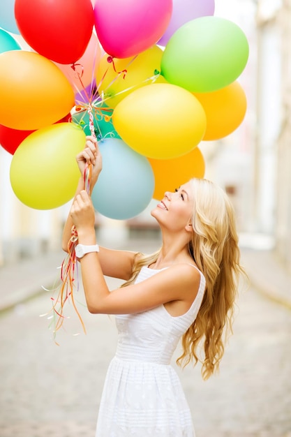 vacaciones de verano, celebración y concepto de estilo de vida - hermosa mujer con globos de colores en la ciudad