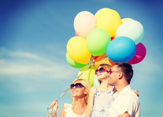 vacaciones de verano, celebración, concepto de niños y personas - familia feliz con globos coloridos al aire libre