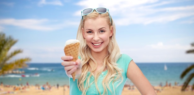 vacaciones de verano, comida chatarra de viaje y concepto de personas - mujer joven o adolescente con gafas de sol comiendo helado sobre una playa tropical exótica con palmeras y fondo marino