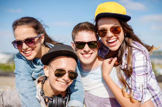 Foto vacaciones de verano y concepto adolescente - grupo de adolescentes sonrientes colgando afuera