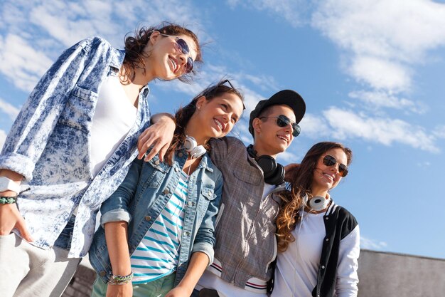 Vacaciones de verano y concepto adolescente - grupo de adolescentes sonrientes con gafas de sol colgando fuera