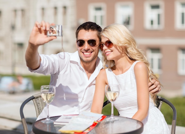 vacaciones de verano y concepto de citas - pareja tomando fotos en un café en la ciudad