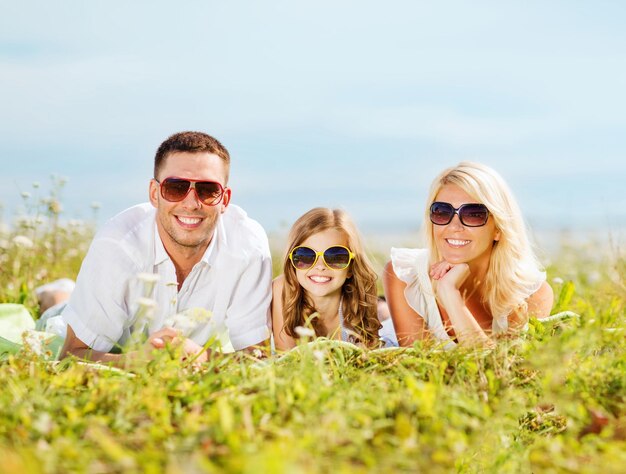 Vacaciones de verano, concepto de niños y personas - familia feliz con cielo azul y pasto verde