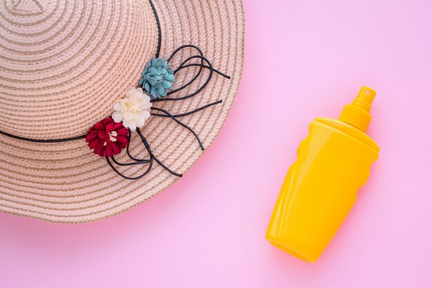 Vacaciones de verano, concepto de protección. Sombrero de mimbre y protector solar en botella.