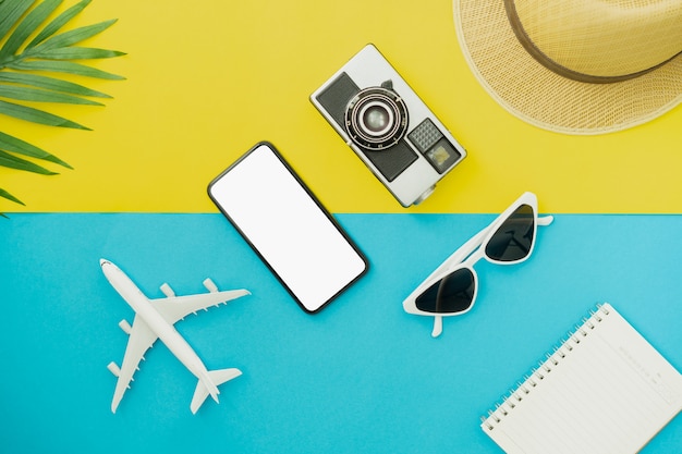 Vacaciones de verano y concepto de viaje. Vista superior del teléfono inteligente negro y gafas con cámara