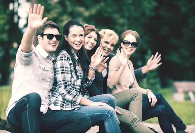 vacaciones de verano, educación, campus y concepto adolescente - grupo de estudiantes o adolescentes agitando las manos