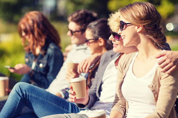 vacaciones de verano, educación, campus y concepto adolescente - grupo de estudiantes o adolescentes con tazas de café para llevar colgando